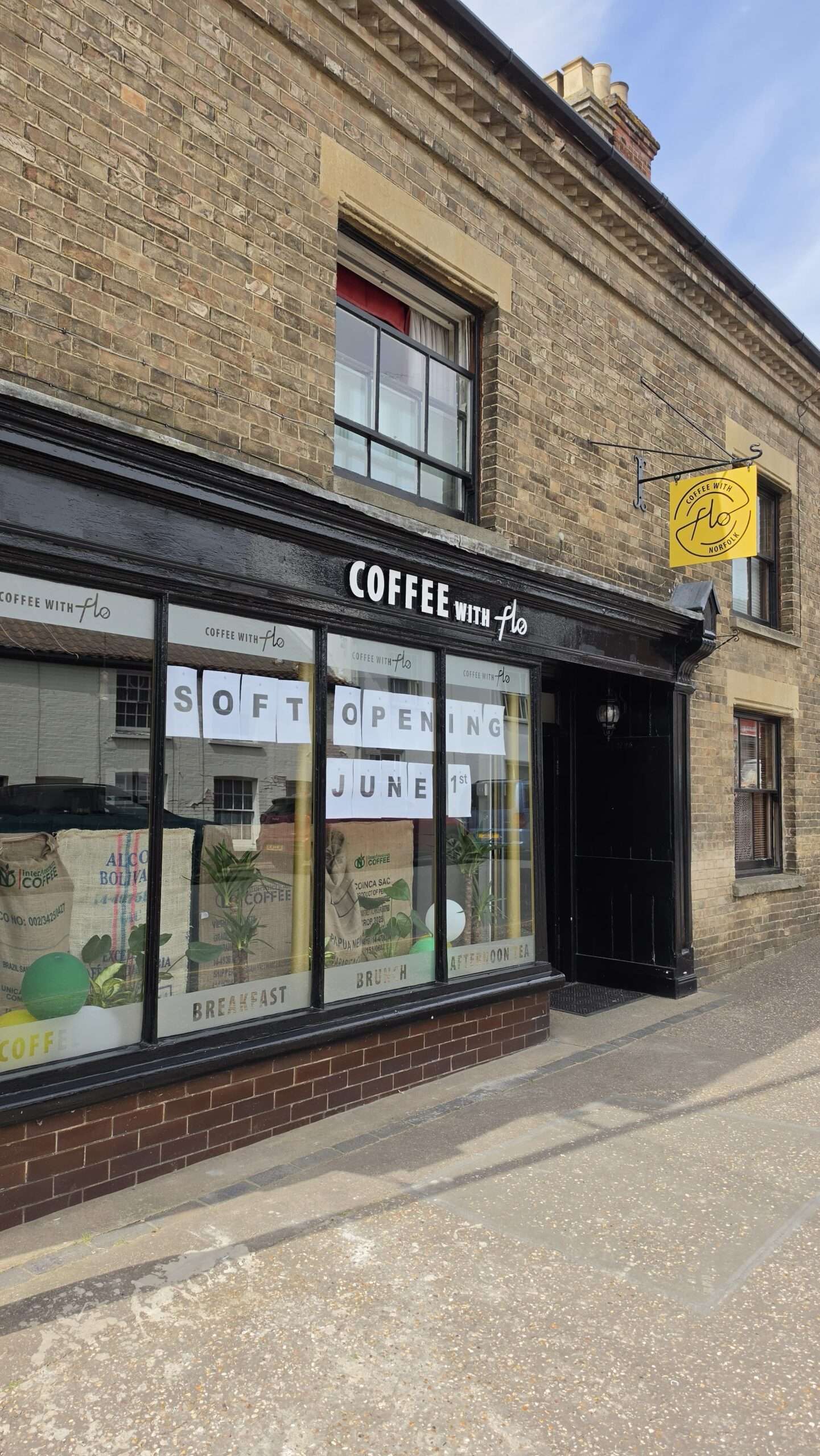 Exterior of Coffee with Flo on Fairland Street, Wymondham, with café signage and large front windows.