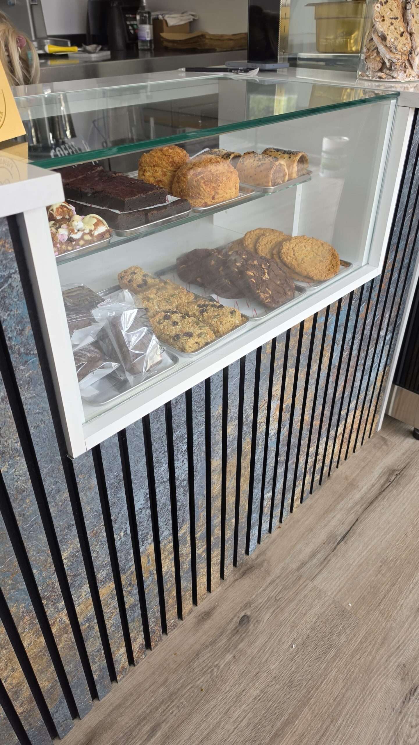 Display cabinet at Coffee with Flo featuring cakes, cookies, pastries and savoury baked goods.